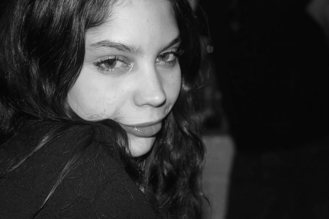 Portrait en noir et blanc de Leila Mouttaqui, de trois quarts, cheveux bouclés sur l'épaule